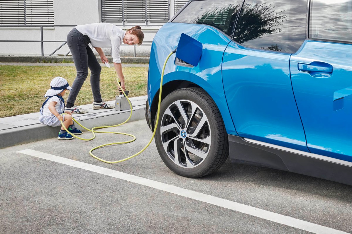 An einem E-Auto-Ladepunkt ist ein blaues Auto angeschlossen.