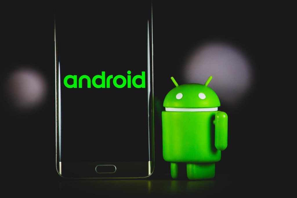 Smartphone mit Android-Schriftzug und Android-Figur daneben
