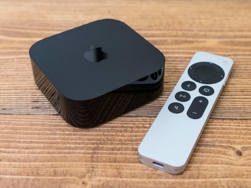 Das Apple TV 4K (2022) samt Fernbedienung auf einem Holztisch.