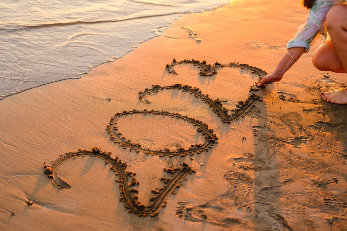 Der Schriftzug 2023 auf einem Strand bei Sonnenuntergang.