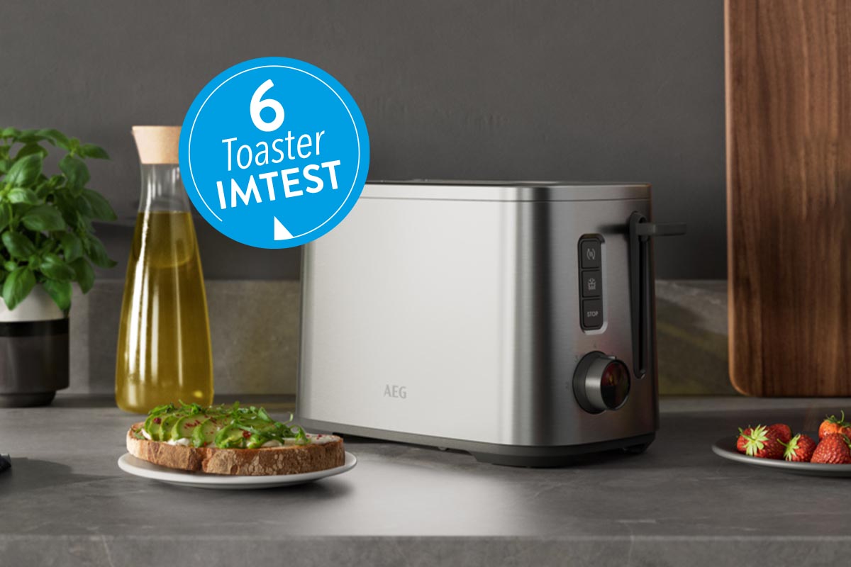 Silberner Toaster auf grauer Arbeitsplatte neben Flasche Öl und Teller mit blauem Button 6 Toaster IMTEST
