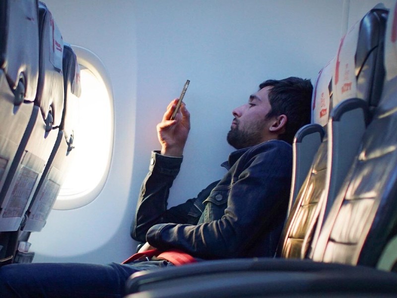 Mann im Flugzeug am Handy