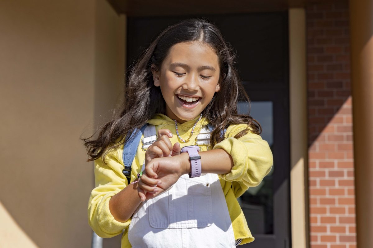 Ein lachendes Mädchen blickt auf ihre Garmin Smartwatch.