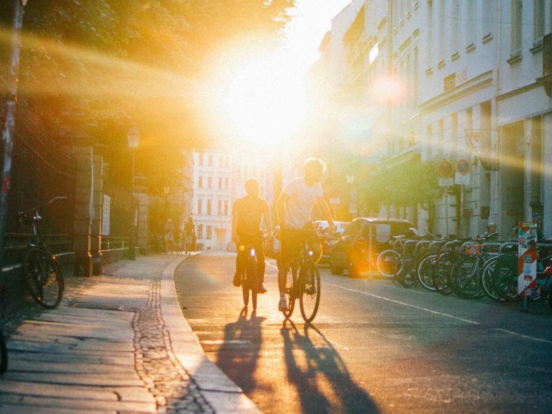 Zwei Personen fahren Fahrrad in einer leeren Straße.