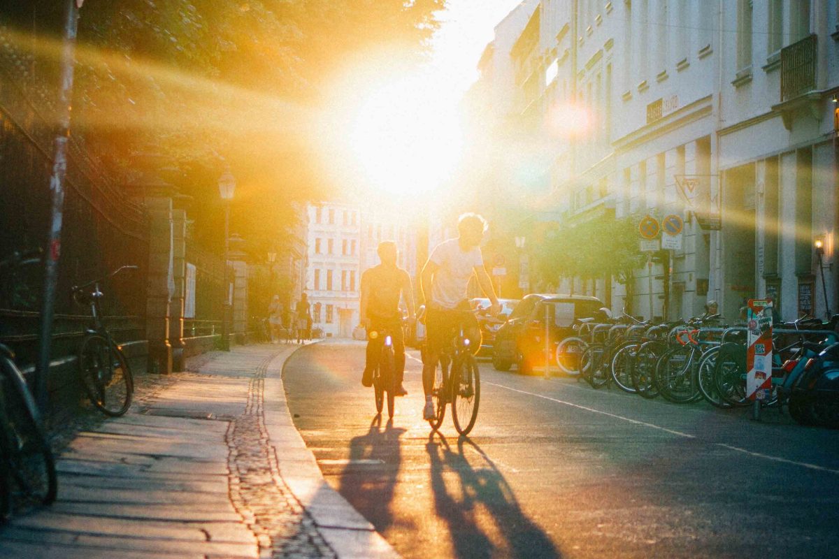 Zwei Personen fahren Fahrrad in einer leeren Straße.