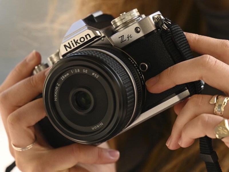 Das Objektiv auf der Nikon Z fc; ein Fotograf hät die Kameras ans Auge