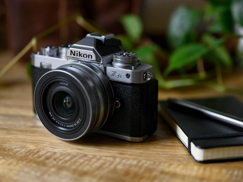 Die Nikon Z fc auf einem Hoilztisch neben einem Leder-Notizbuch