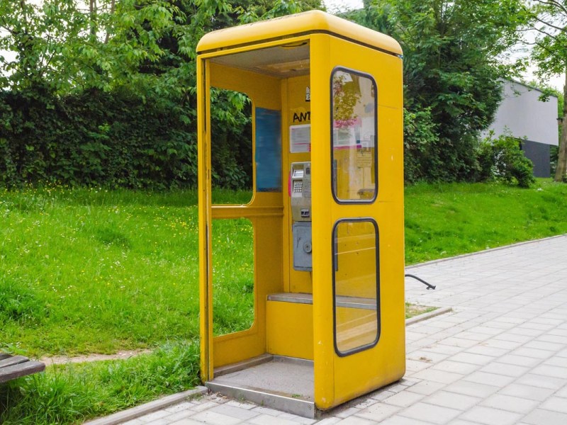 Eine gelbe Telefonzelle auf einem Brügersteig