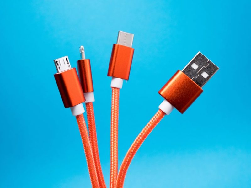 Vier orangene Ladekabel vor einem blauen Hintergrund.