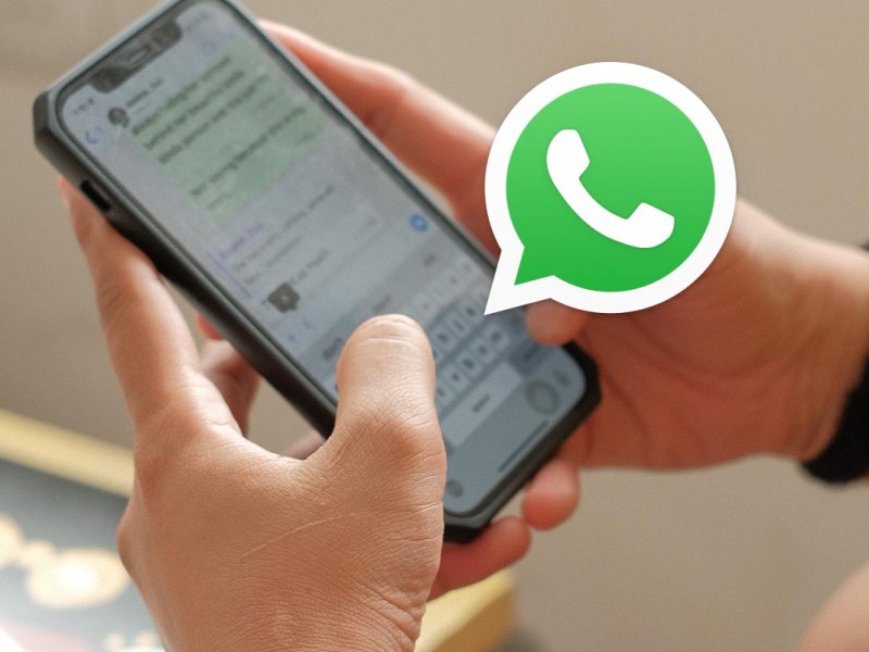Jemand tippt auf Smartphone, Whatsapp-Icon im Vordergrund