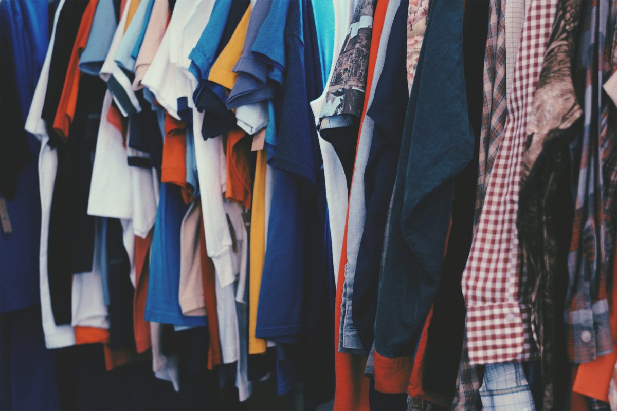 Verschieden farbige Kleidung hängt an einer Kleiderstange.