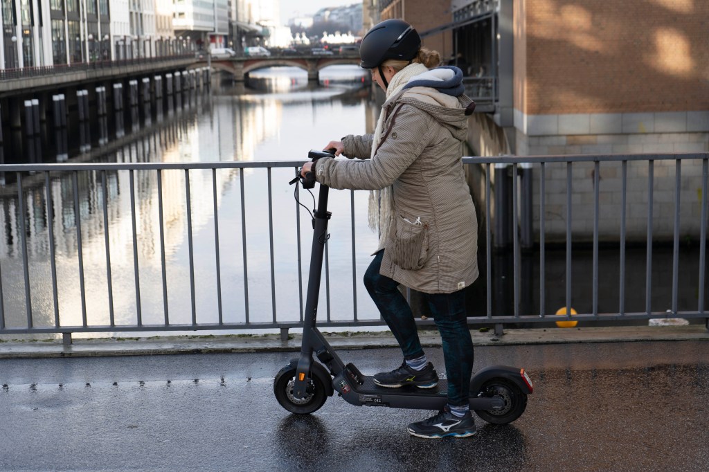 Eine junge Frau fährt mit E-Roller.