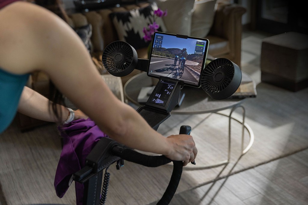 Detaiaufnahme des smarten Indoor-Training-Bikes Tacx NEO Bike Plus von Garmin: Fahrerin schaut auf das Display des smarten Bikes.
