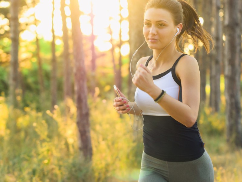 Frau joggt durch sonnige Landschaft