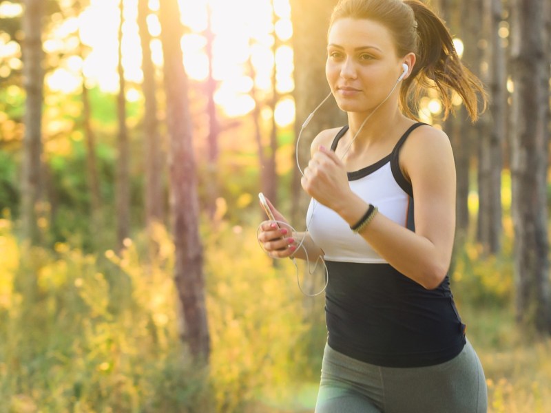 Frau joggt durch sonnige Landschaft