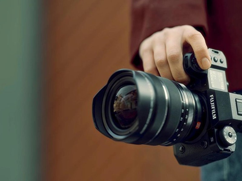Ein Fotograf hält die Kamera mit einer Hand auf Hüfthöhe