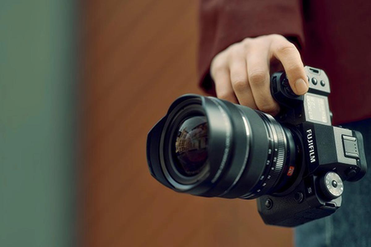 Ein Fotograf hält die Kamera mit einer Hand auf Hüfthöhe