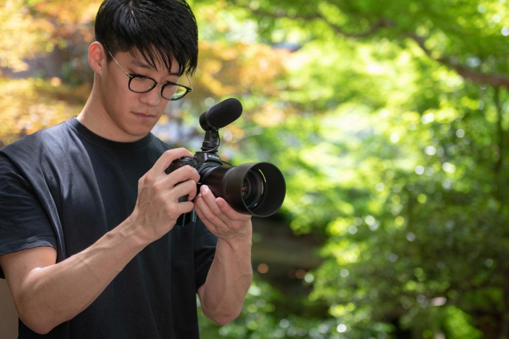 Die Nikon Z5 mit aufgesetztem Mikrofon in der Hand eines Fotografen