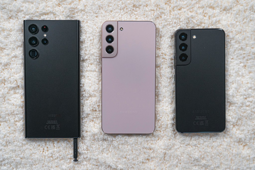 Drei unterschiedlich große Smartphones liegen mit Rückseite nach oben auf weißem Teppich