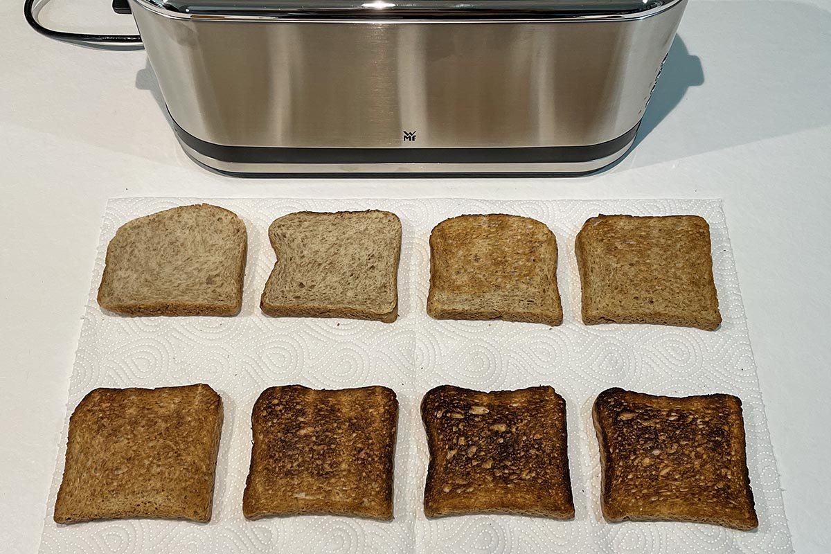 Zwei Viererreihen Toast unterschiedlich gebräunt, oben im Bild silberner Toaster