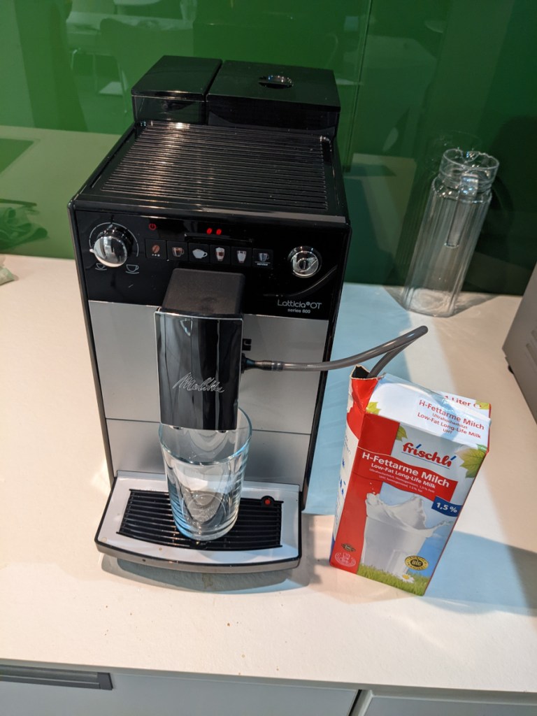 Silberner Kaffeevollautomat im TEst von oben mit Milchtüte daneben