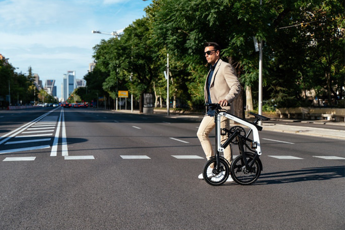 Mann schiebt geklapptes E-Faltbike über eine Straße