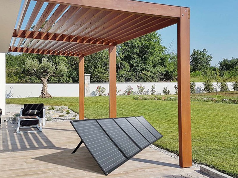 Mobiles Sonnenpanel steht ausgebreitet auf einer Terrasse im Garten