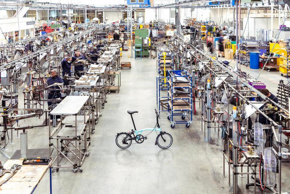 E-Faöt-Bike von Brompton steht in einer Fabrik vor Regalen.