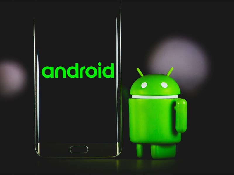Das Android-Maskottchen neben einem Smartphone.