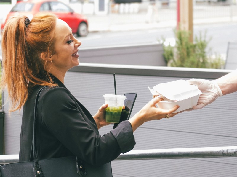 Eine Frau nimmt auf der Straße Essen entgegen.