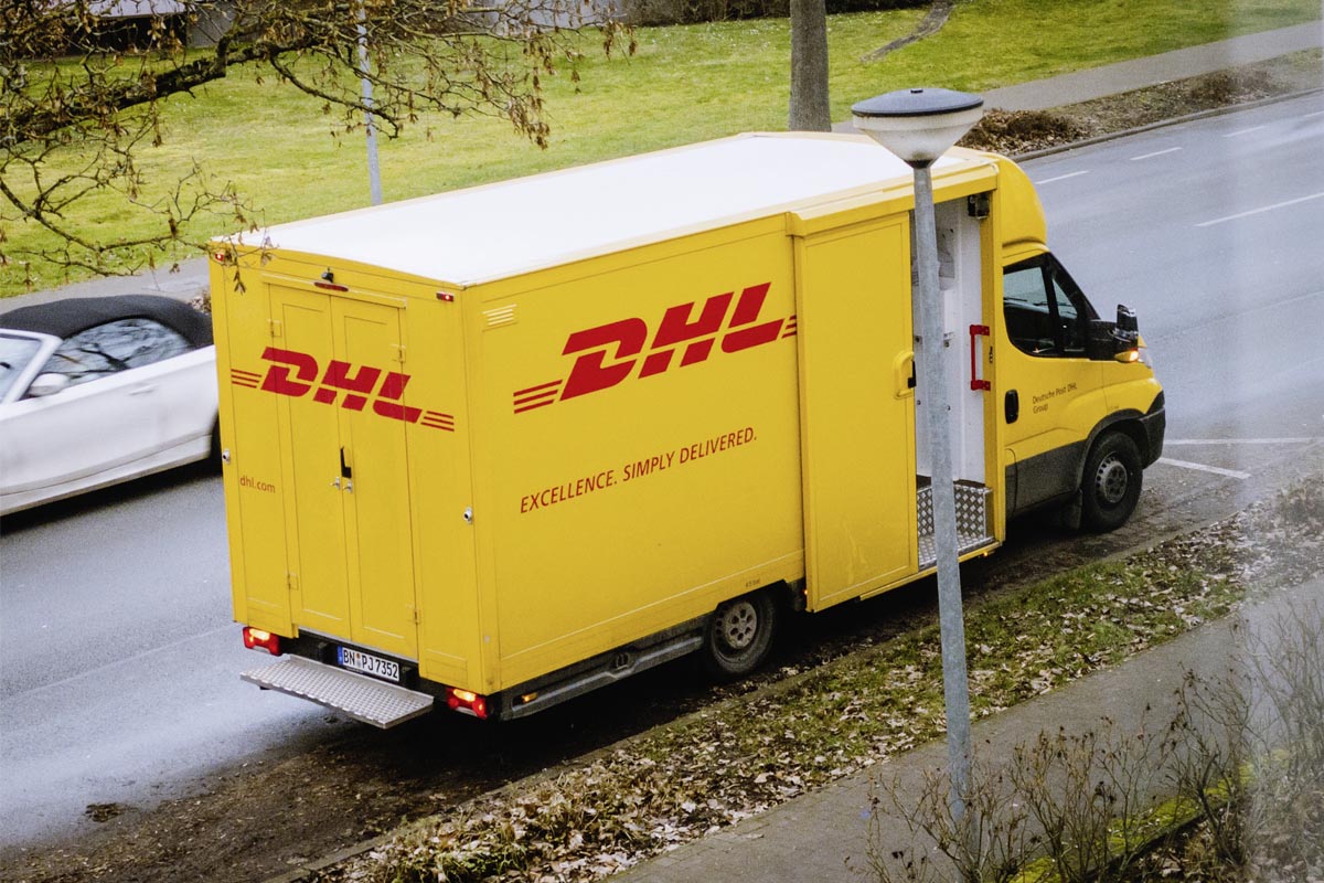 Ein DHL-Wagen parkt an einer Straße.