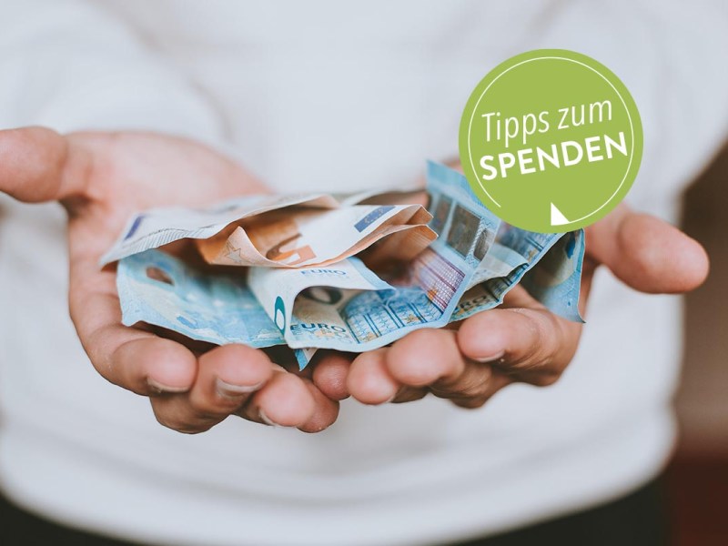 Mensch hält Euro-Scheine vor sich