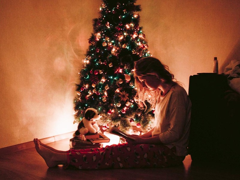 Frau sitzt neben Tannenbaum auf dem Boden