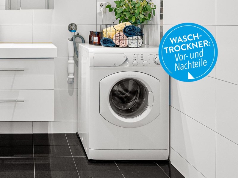 Eine Waschmaschine im Badezimmer auf schwarzen Fliesen stehend