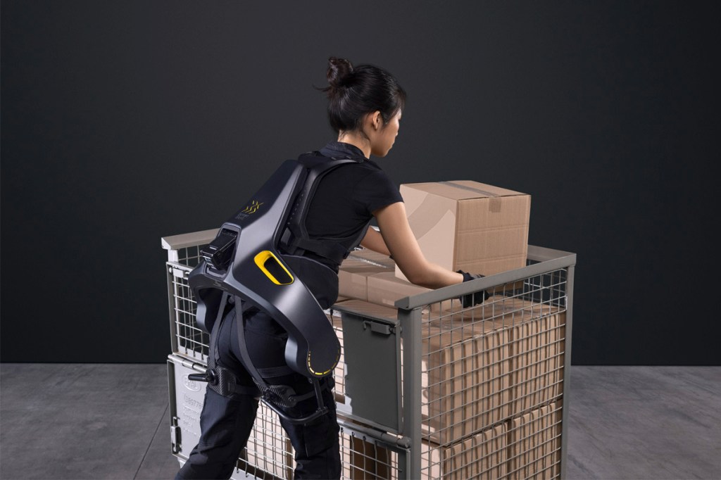 Eine Frau trägt das Exoskelett Apogee beim Heben von Paketen.