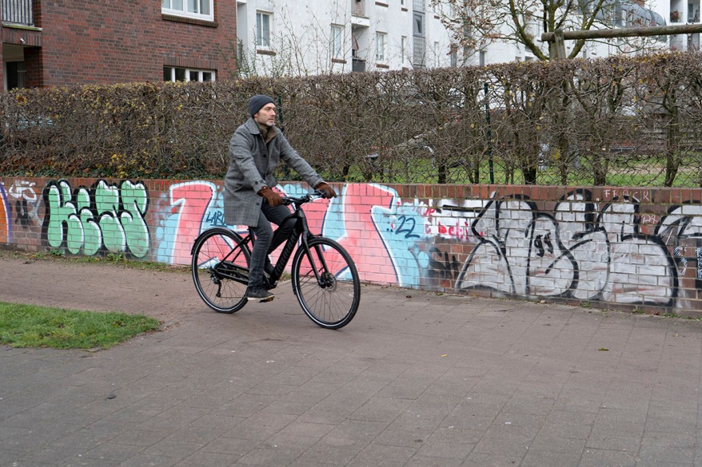 Mann fährt auf Damen-E-Bike in Stadtlandschaft