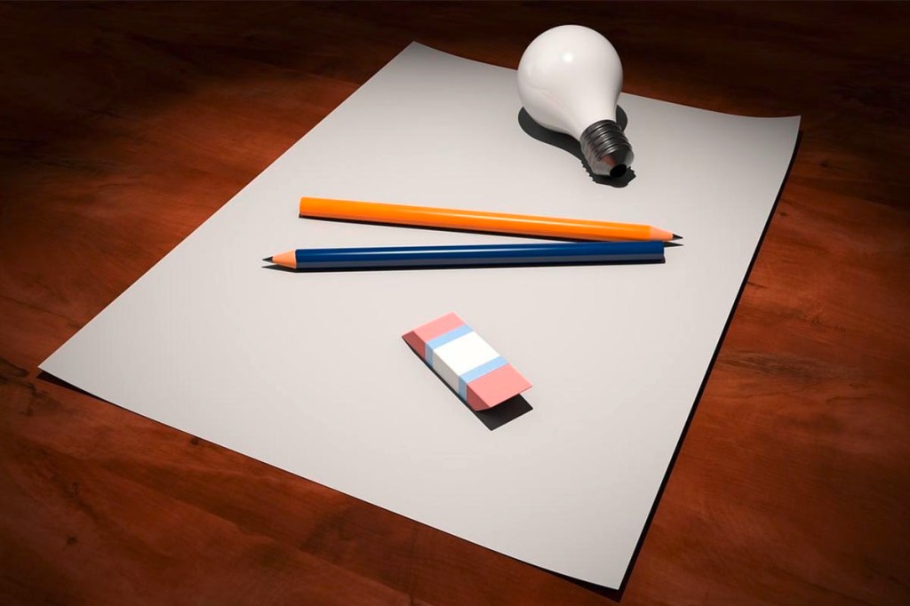 Stifte, Glühbirne und Radiergummi auf einem weißen Blatt Papier