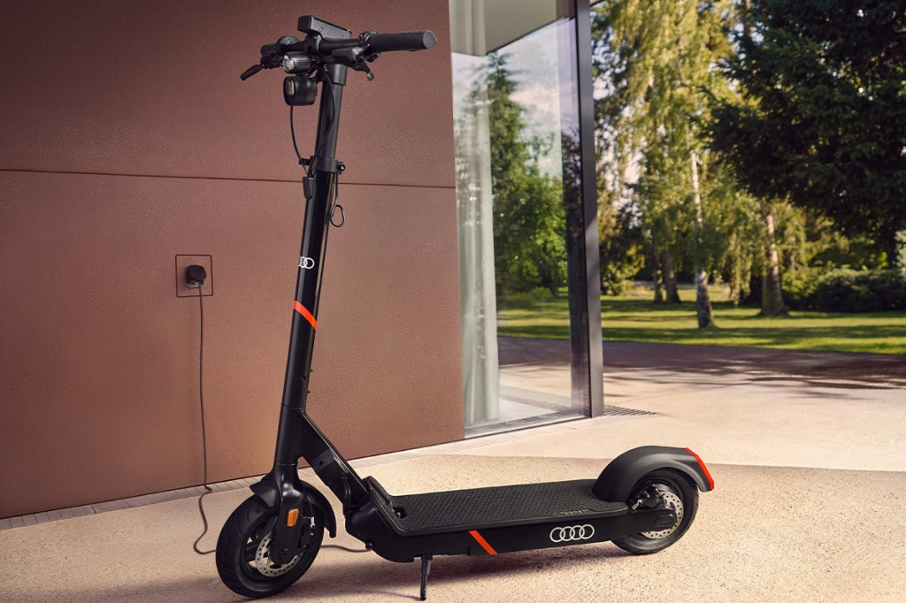 Audi electric kick scooter powered by Egret in einer Garage, wird gerade aufgeladen