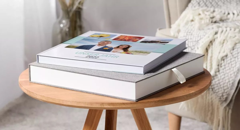 runder Holztisch auf dem ein Fotobuch auf einer Geschenkbox liegt