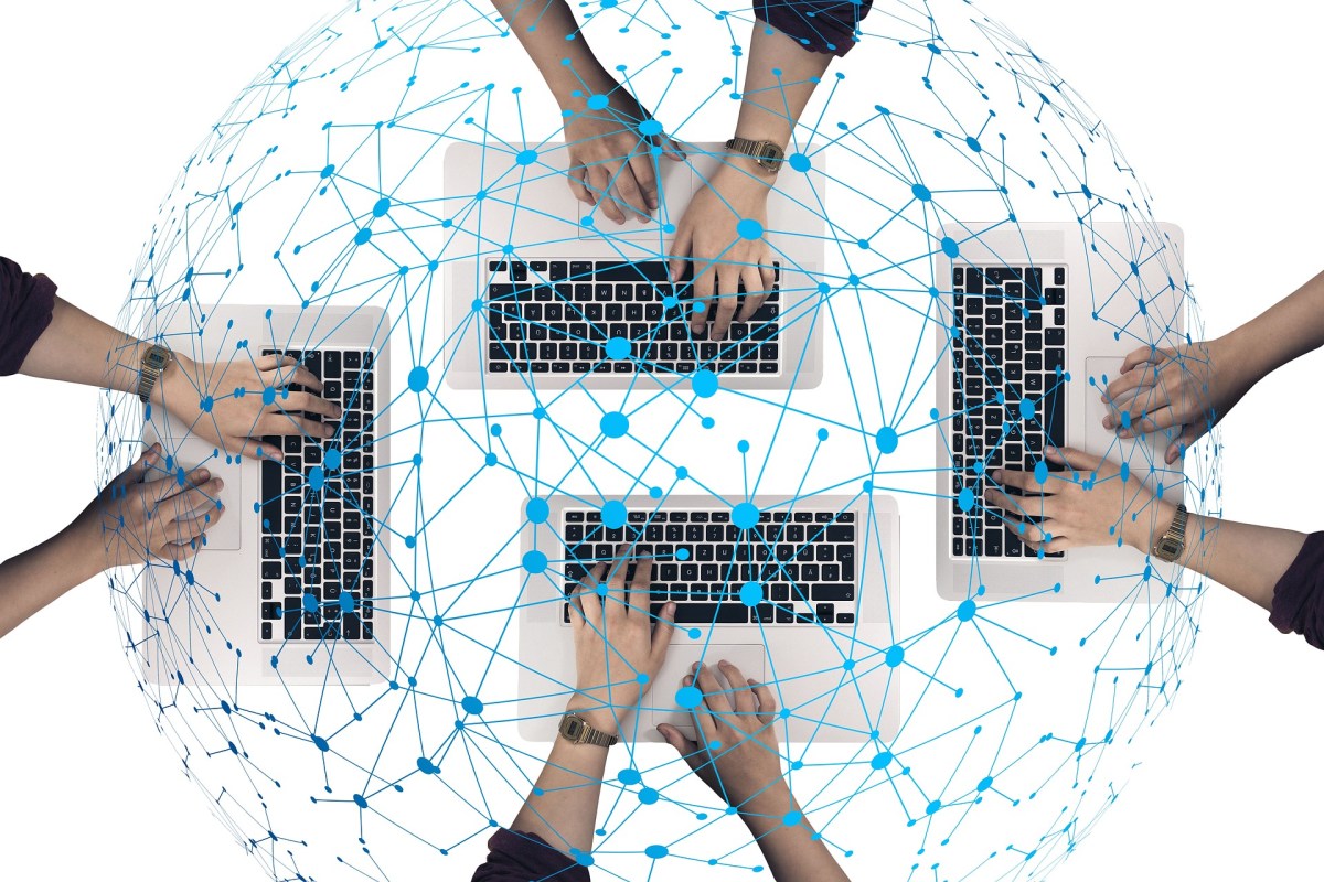 Vier Keyboards mit Händen sind durch ein blaues Netz verbunden.
