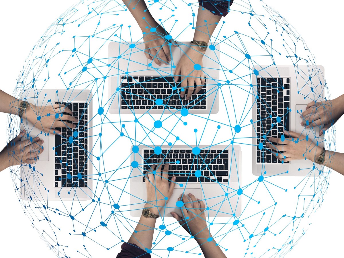 Vier Keyboards mit Händen sind durch ein blaues Netz verbunden.