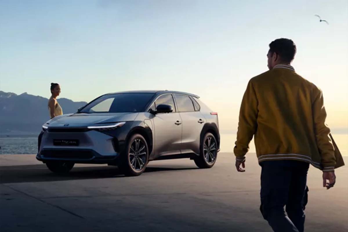 Toyota bZ Compact Concept SUV in Natur vor aufgehender Sonne, zwei Menschen laufen um das Auto herum