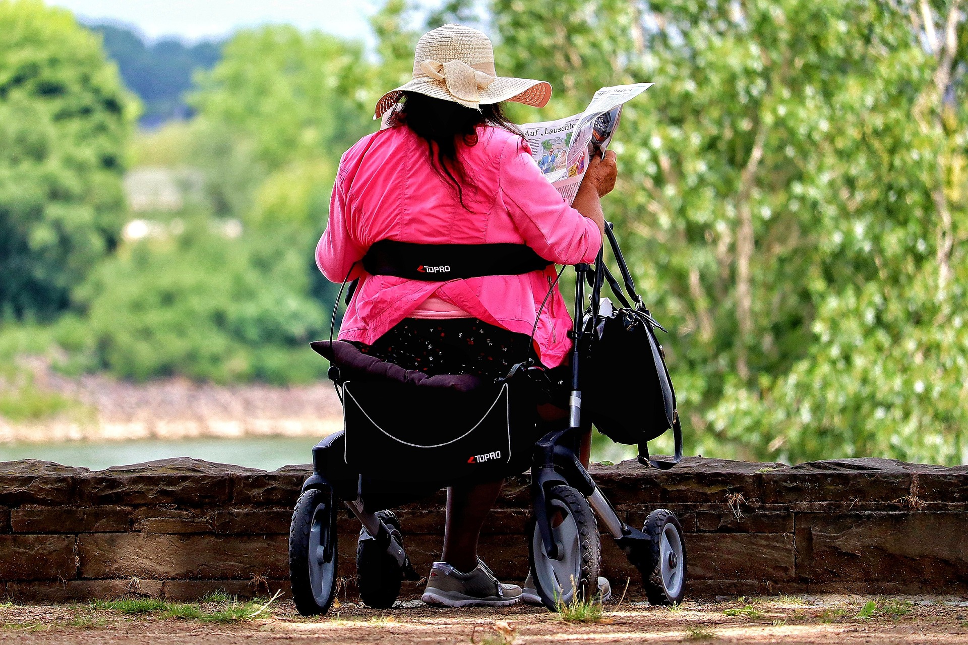 Eine Dame in Pink sitzt auf einem Rollator und studiert eine Karte.