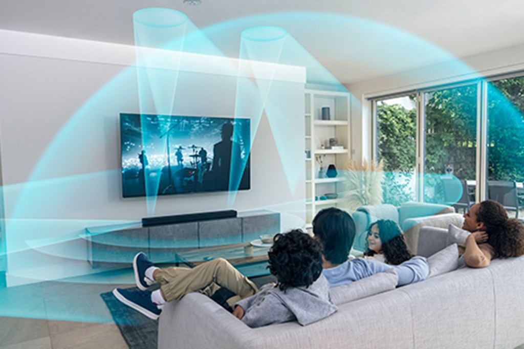 Vier Personen sitzen auf einem Sofa und schauen TV. Der Klang kommt von einer Soundbar. Visualisiert ist das durch Soundwolken, die grafisch in das Bild integriert sind. 