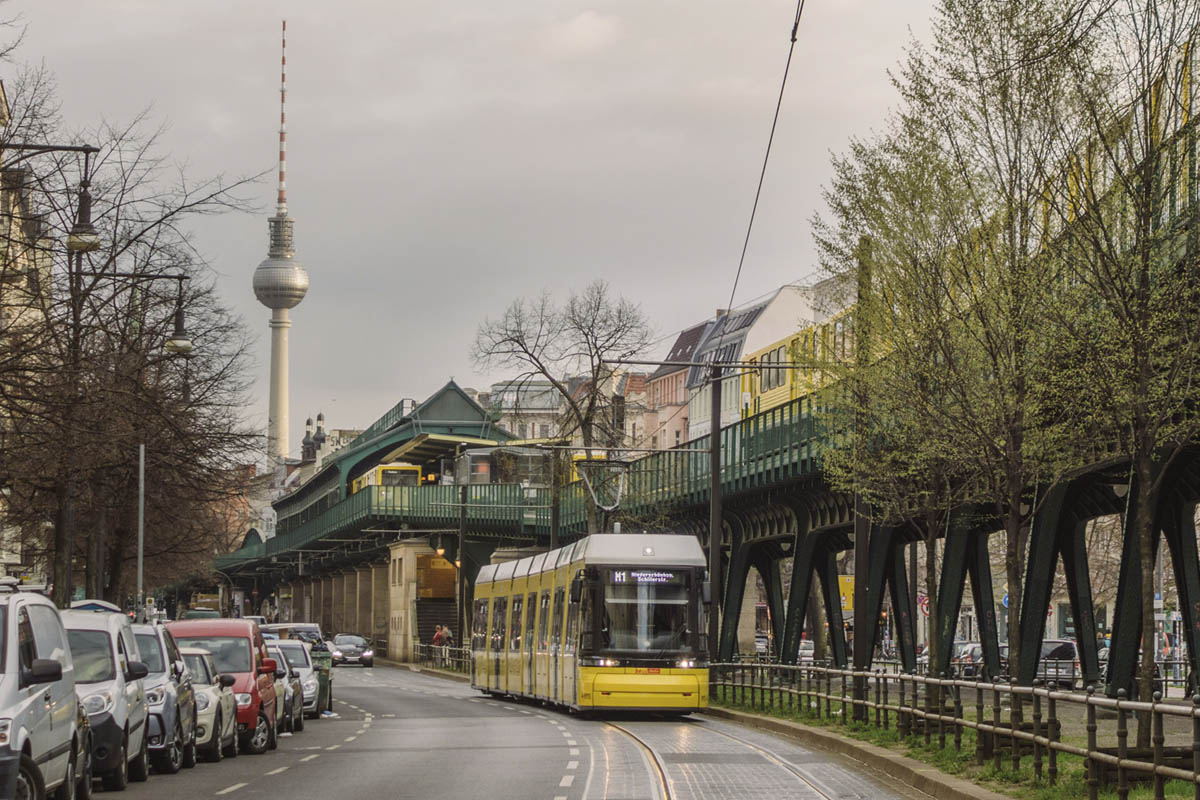 Eine Straßenbahn fährt neben parkenden Autos in Berlin.