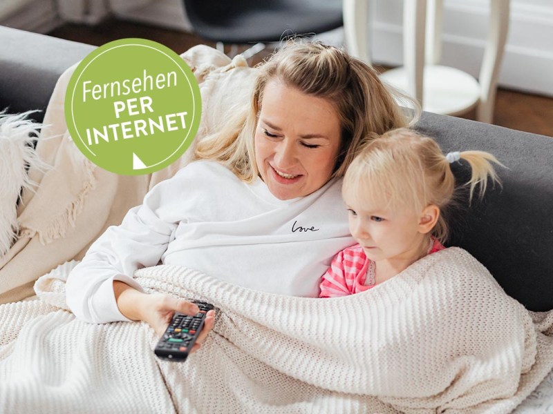 IPTV: Frau und Kind sitzen auf einem Sofa mit Fernbedienung in der Hand