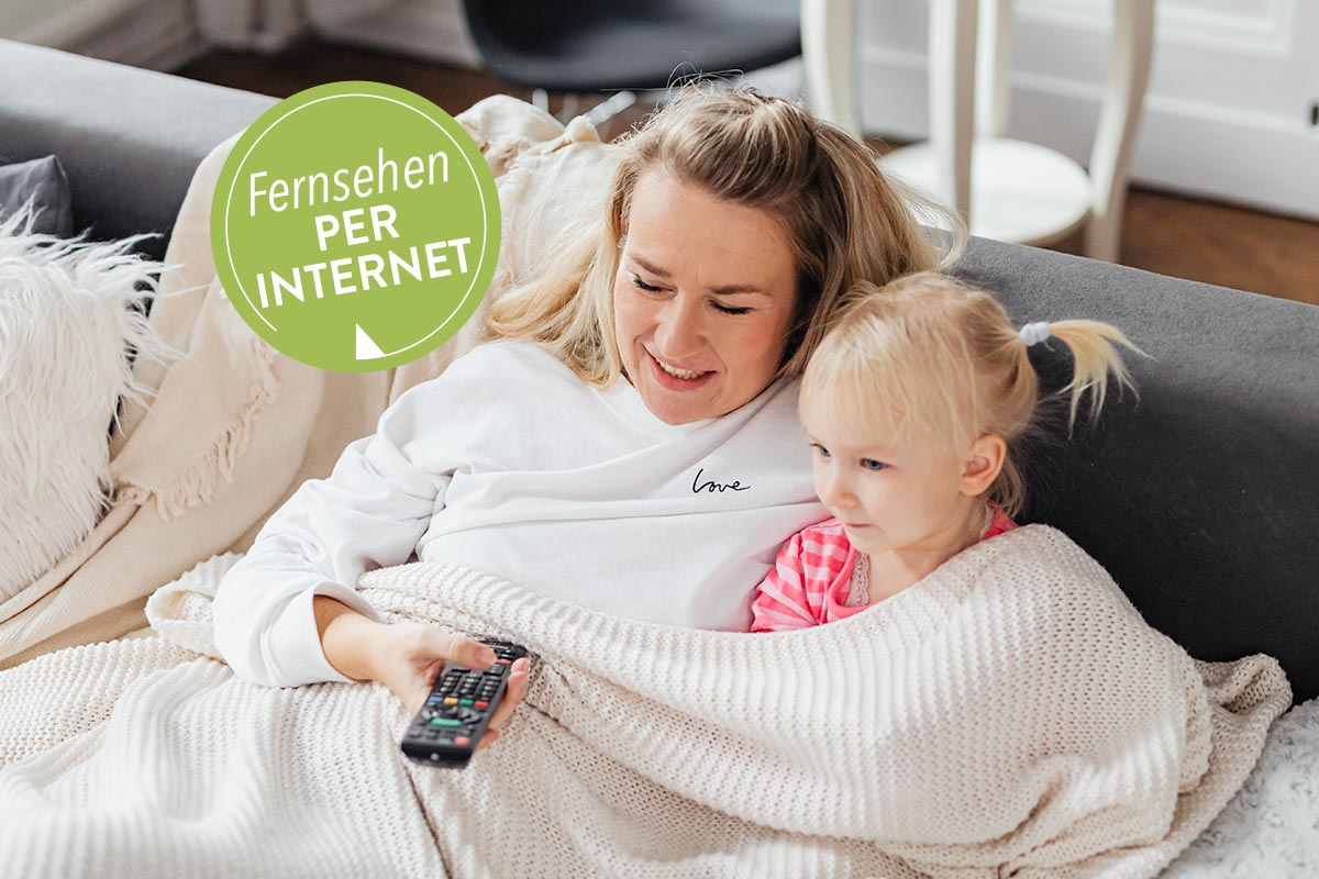 IPTV: Frau und Kind sitzen auf einem Sofa mit Fernbedienung in der Hand