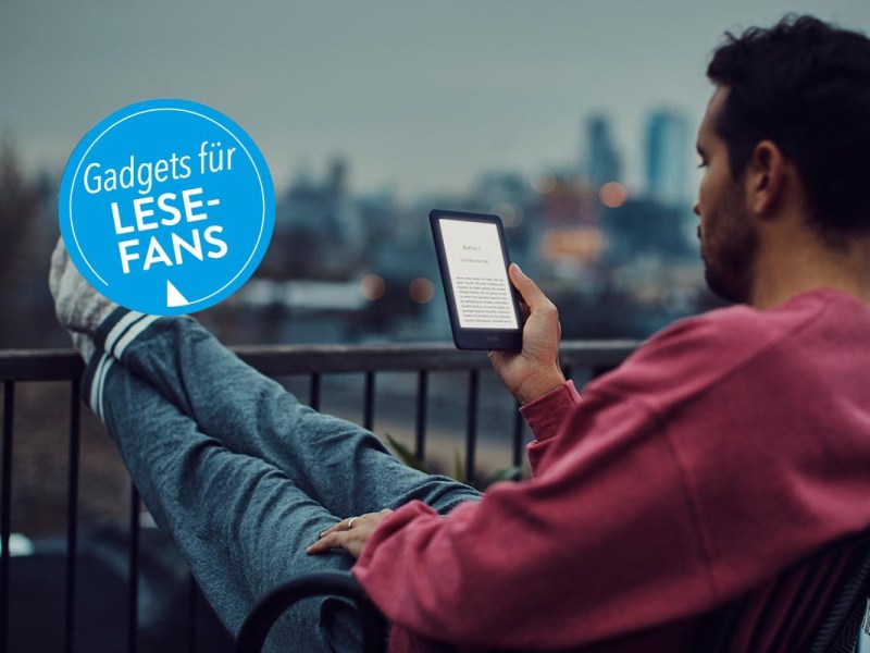 Ein Mann sitzt in der Dämmerung auf dem Balkon und liest in seinem EBook-Reader