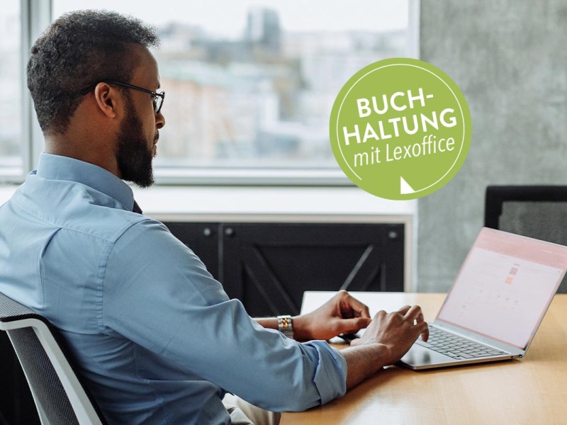 Ein Mann sitzt am Tisch vor einem Laptop