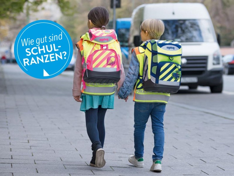 Zwei Kinder mit Schulranzen auf einem Gehweg